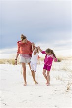 Caucasian mother and children walking on sand dune