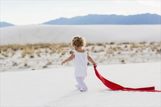 Caucasian boy playing with scarf on sand dune