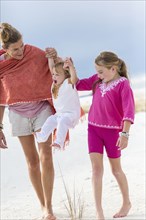 Caucasian mother and children playing on sand dune