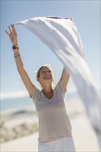 Caucasian woman playing with scarf on sand dune