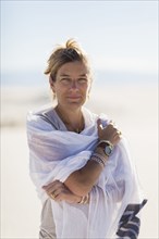 Caucasian woman wrapped in scarf on sand dune