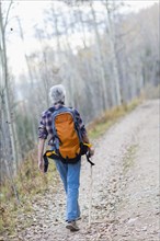 Caucasian hiker walking on dirt path in forest