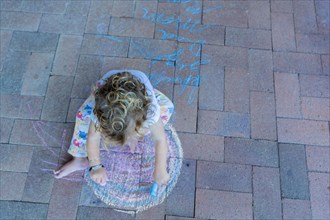 Caucasian boy drawing with chalk on patio