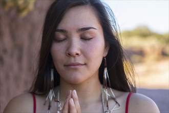 Mixed race woman praying in desert