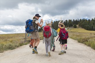 Caucasian hiker leading children on path in remote landscape