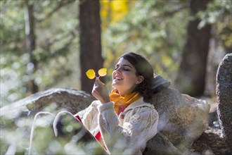 Mixed race woman admiring autumn leaves in forest