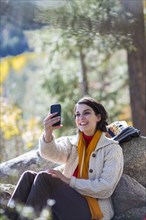 Mixed race hiker taking cell phone selfie in forest