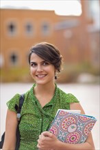 Mixed race student carrying books on campus