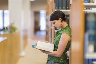 Mixed race student reading book in library