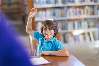 Student raising his hand in library