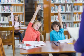 Students raising their hands in library