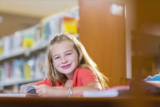 Caucasian student smiling at desk in library