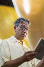 Older Caucasian man reading book in library