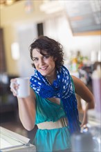 Mixed race woman holding cup of coffee in cafe