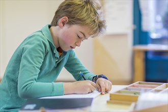 Caucasian boy writing in classroom