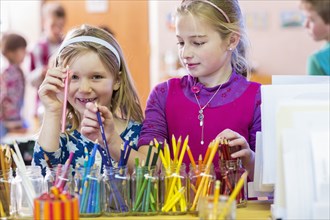 Caucasian girls choosing multicolor pencils in classroom