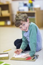 Smiling boy drawing in classroom