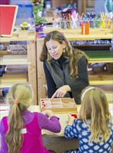 Montessori teacher helping students in classroom