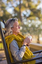 Older Caucasian woman drinking coffee in rocking chair