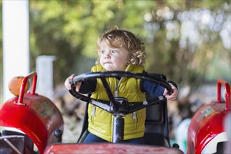 Caucasian baby boy driving tractor