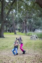 Caucasian children playing on swing in park
