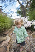 Caucasian baby boy walking in garden