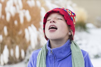 Caucasian girl catching snowflakes on tongue
