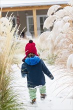 Caucasian baby boy walking in snowy garden