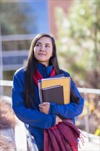 Mixed race student holding books on campus