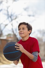 Caucasian boy playing basketball outdoors