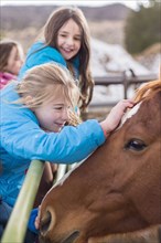 Caucasian girls petting horse on ranch