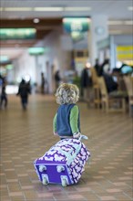 Caucasian baby boy rolling luggage in airport