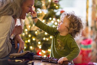 Caucasian grandmother and grandson playing with toys near Christmas tree