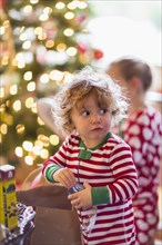 Caucasian baby boy opening present near Christmas tree