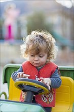 Caucasian baby boy driving toy tractor