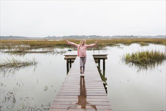 Caucasian girl standing on wooden dock over lake