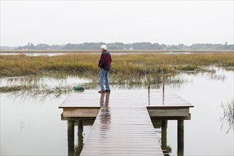 Older Caucasian man standing on wooden dock over lake