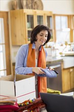 Hispanic business owner packing boxes in home office