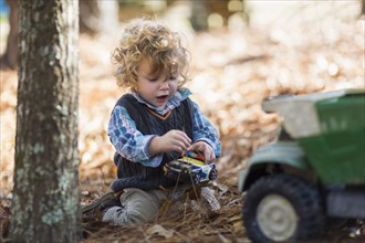 Caucasian boy playing with toy trucks in forest