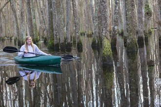 Caucasian woman rowing canoe in river