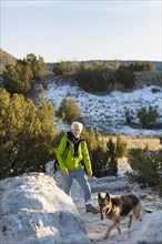 Older man and dog standing on remote rock formations
