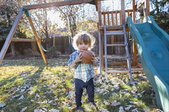 Caucasian boy holding basketball in backyard