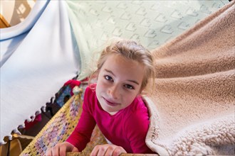 Caucasian girl playing in blanket fort
