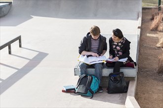 Teenage students studying in skateboard park
