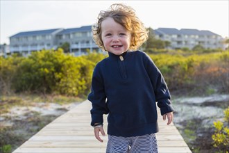 Caucasian baby boy on wooden walkway on beach