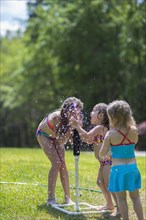 Caucasian girls playing in sprinkler