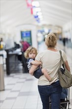 Caucasian mother carrying baby son in airport