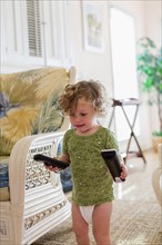 Caucasian baby boy carrying remote controls in living room