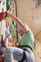 Caucasian girl climbing rock wall indoors
