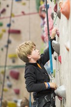 Boy climbing rock wall indoors